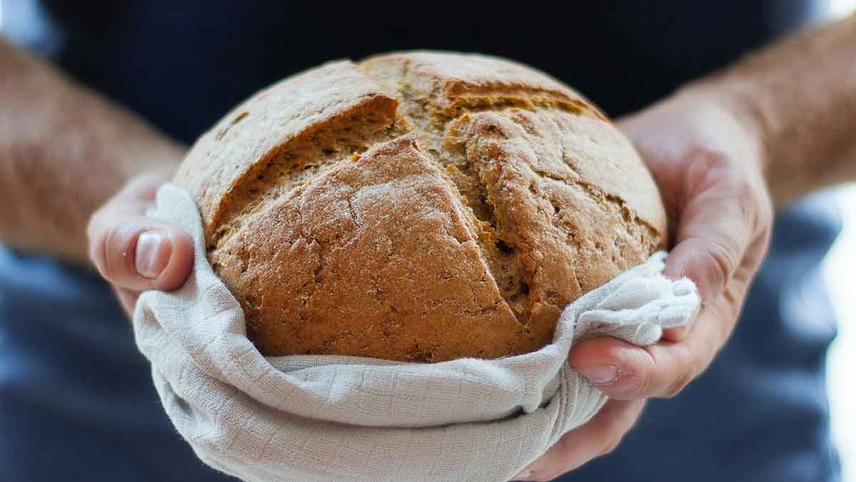 A person holding a loaf of freshly-baked bread