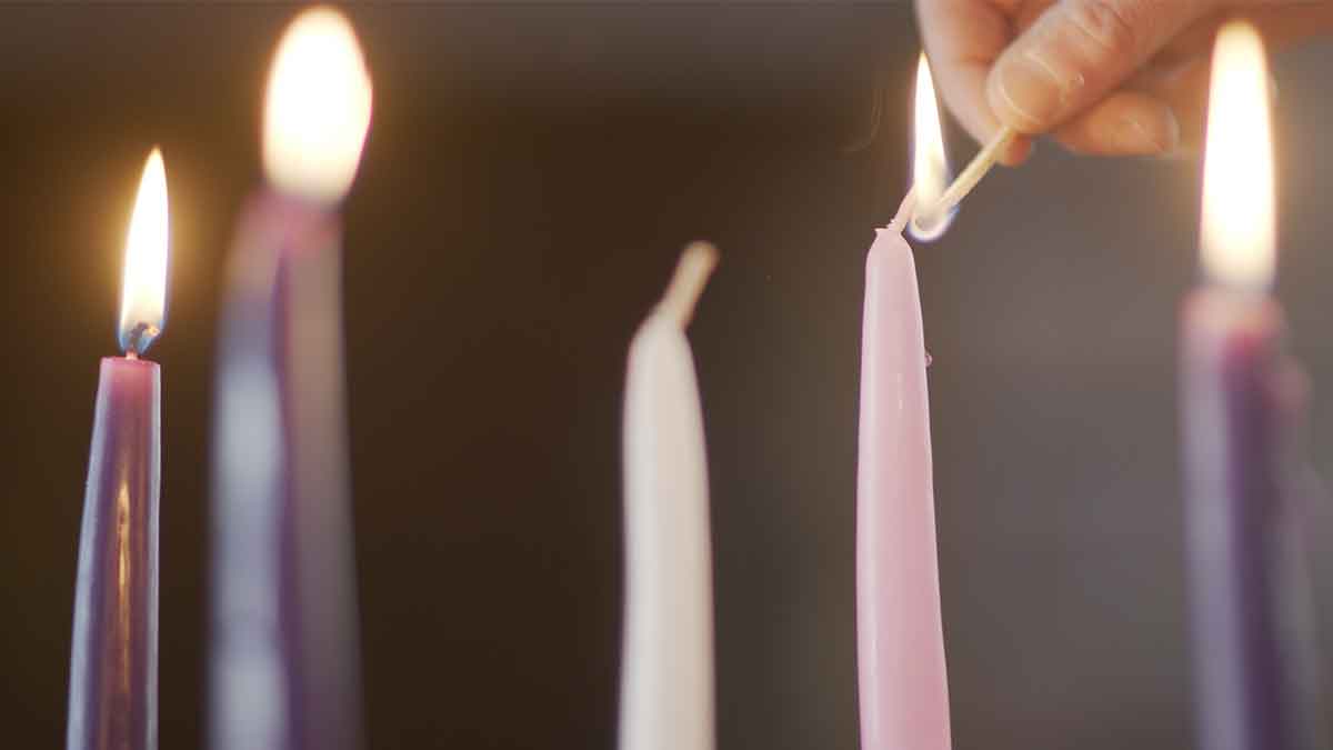 Pink candle being lit on an Advent wreath