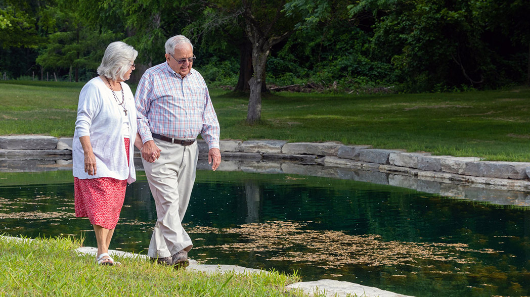 A senior couple walks holing hands at the pond on the grounds of Capuchin Retreat Center in Washington Township, Michigan.