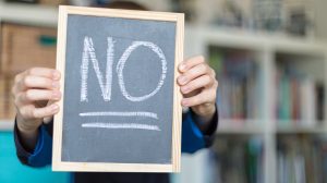 The word "No" written on a chalkboard being held up.