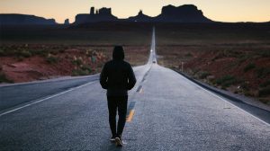 Color photo of a jogger running through Monument Valley, Utah at sunrise or sunset.